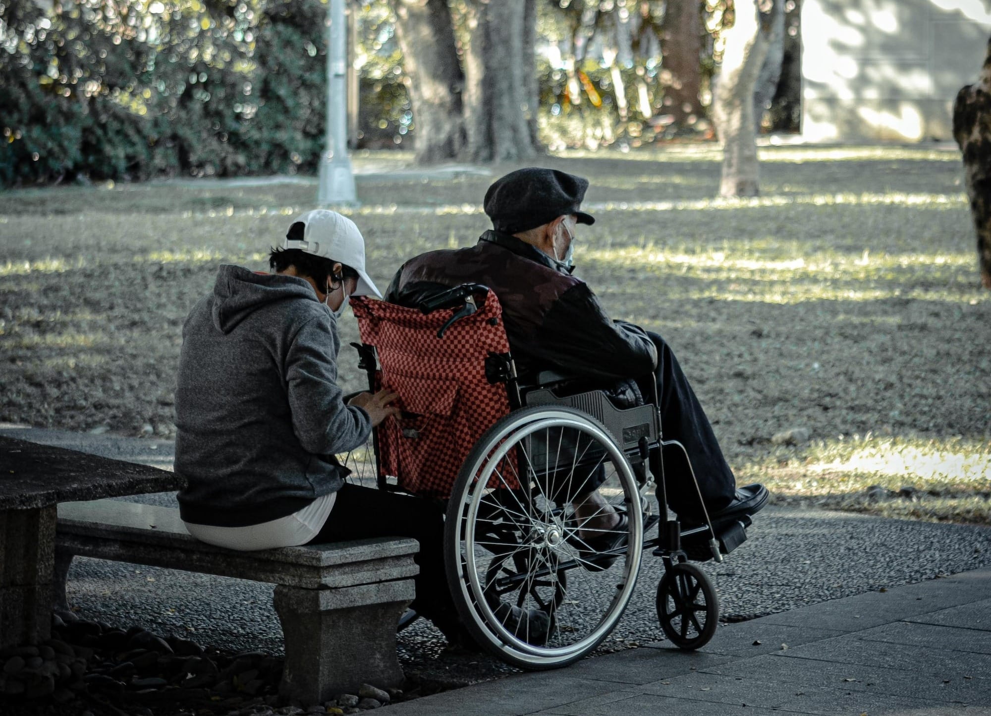 man in black jacket sitting on brown wooden bench during daytime