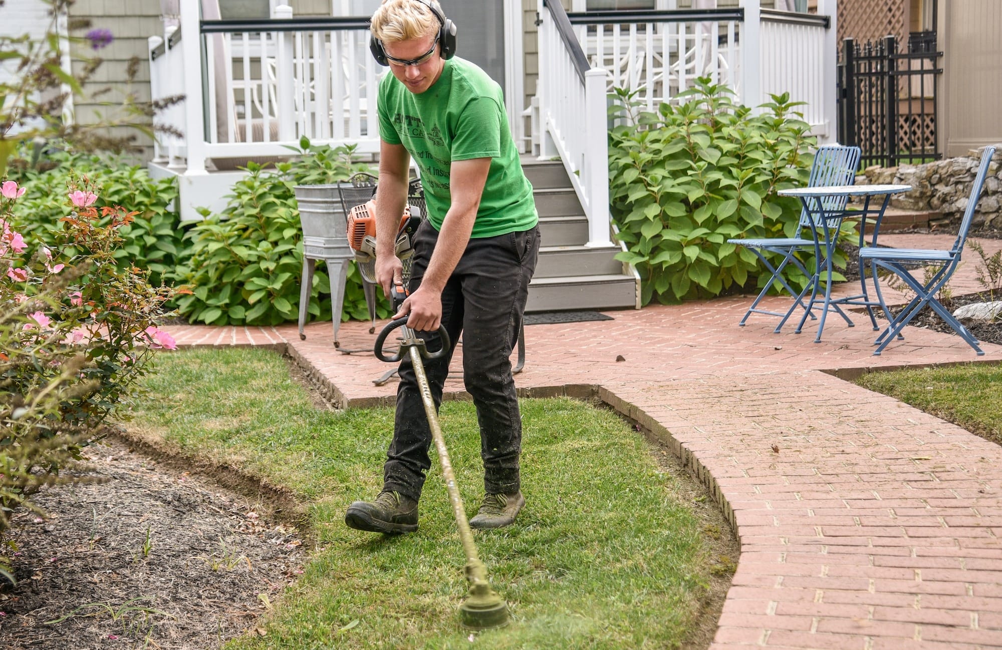 man in green t-shirt and black pants holding black and brown shovel