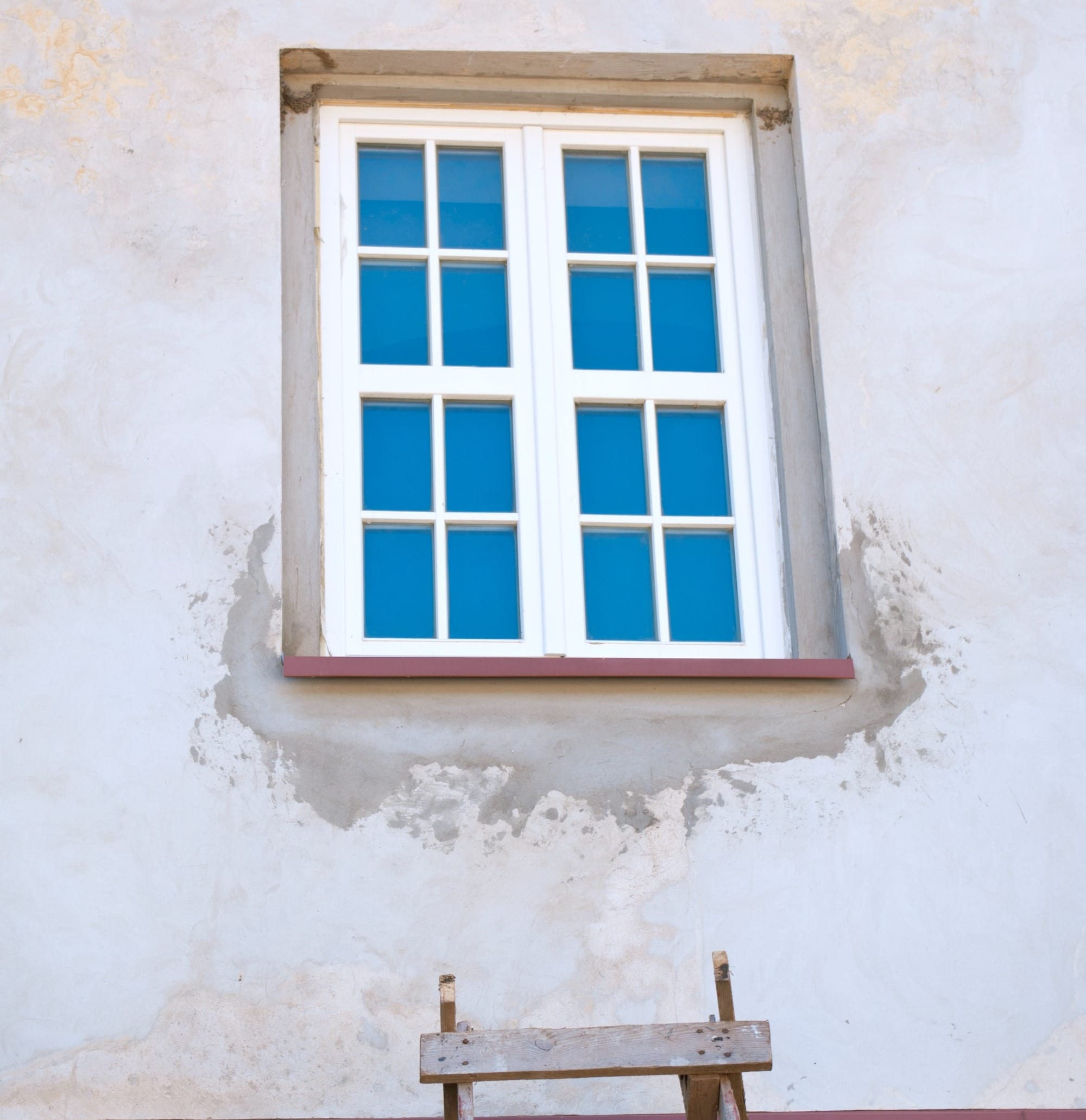 a ladder leaning against a wall with a window above it