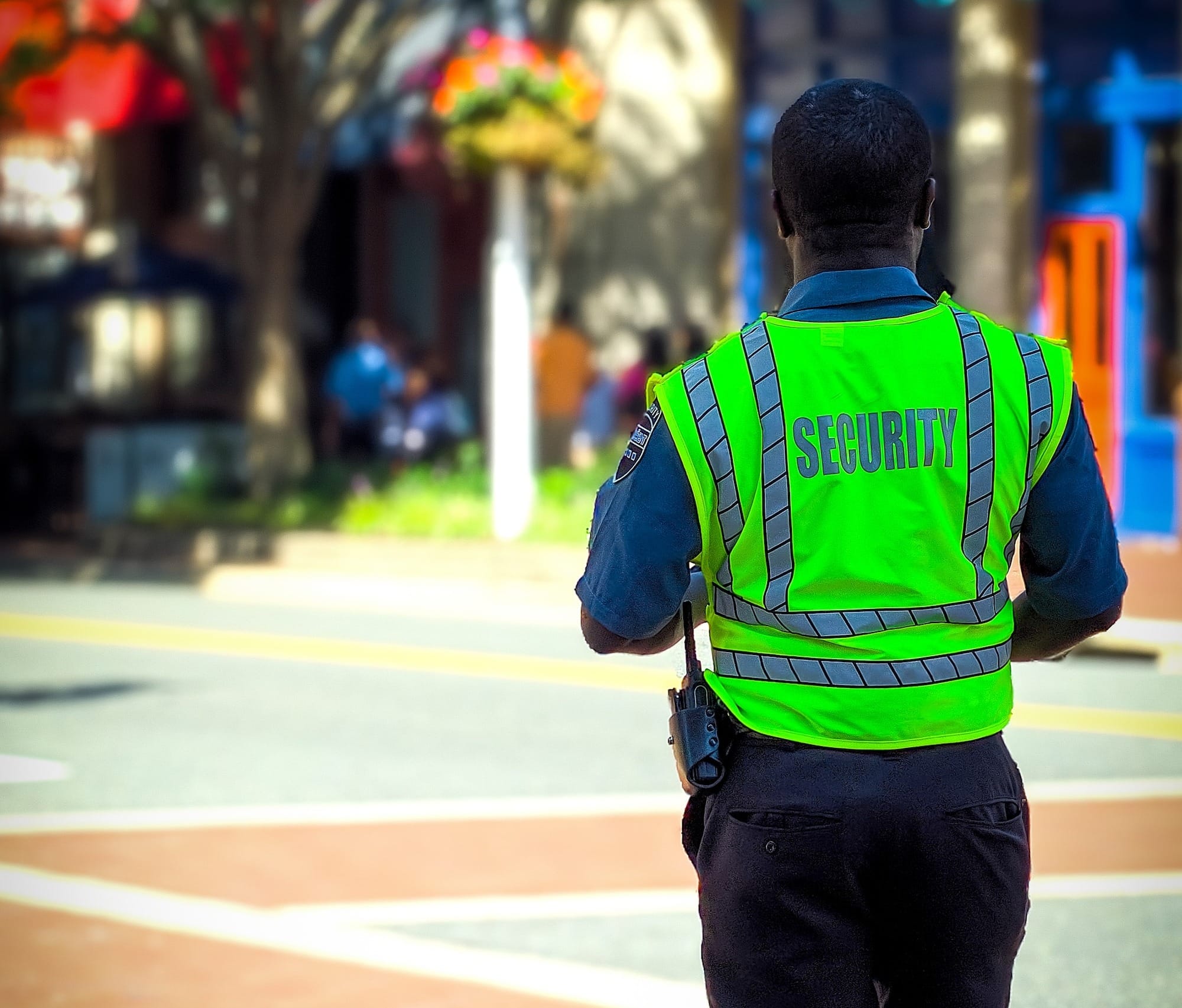 man in green and blue jacket walking on street during daytime