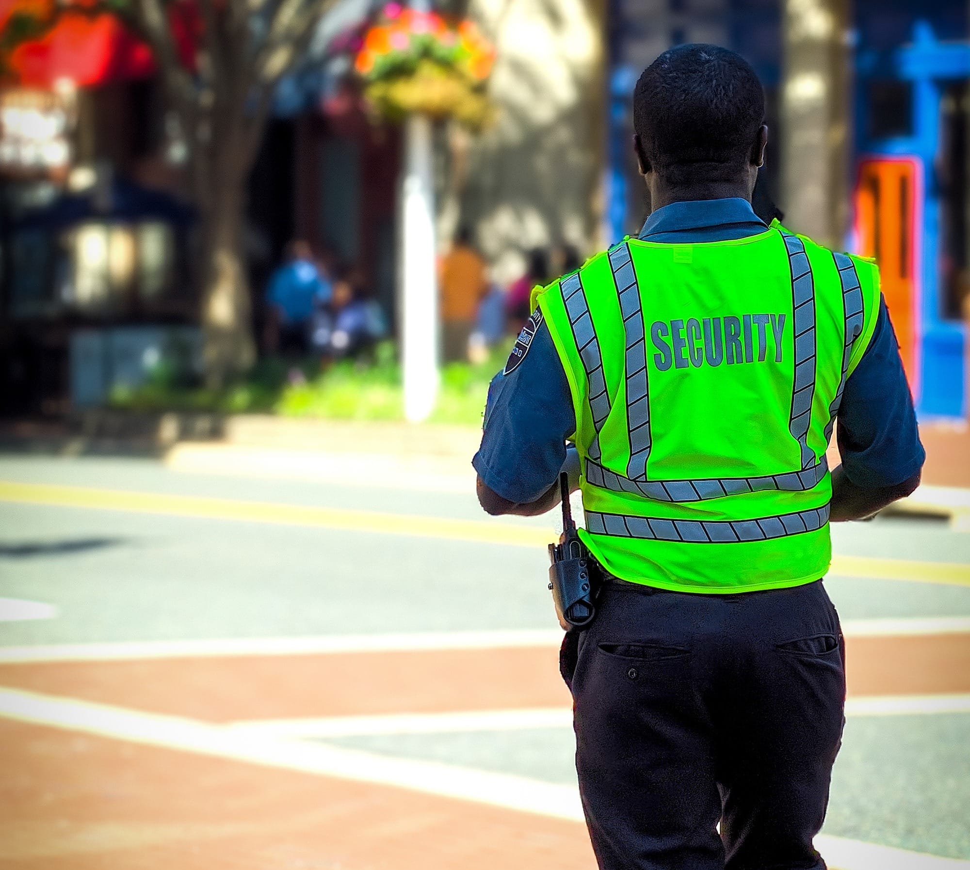 man in green and blue jacket walking on street during daytime