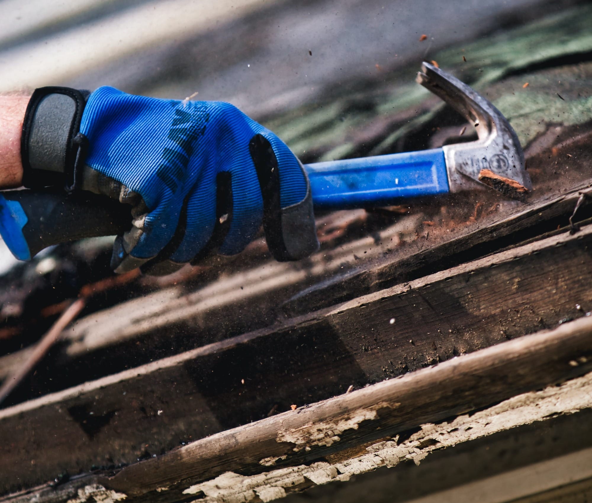 a person wearing blue gloves and holding a hammer