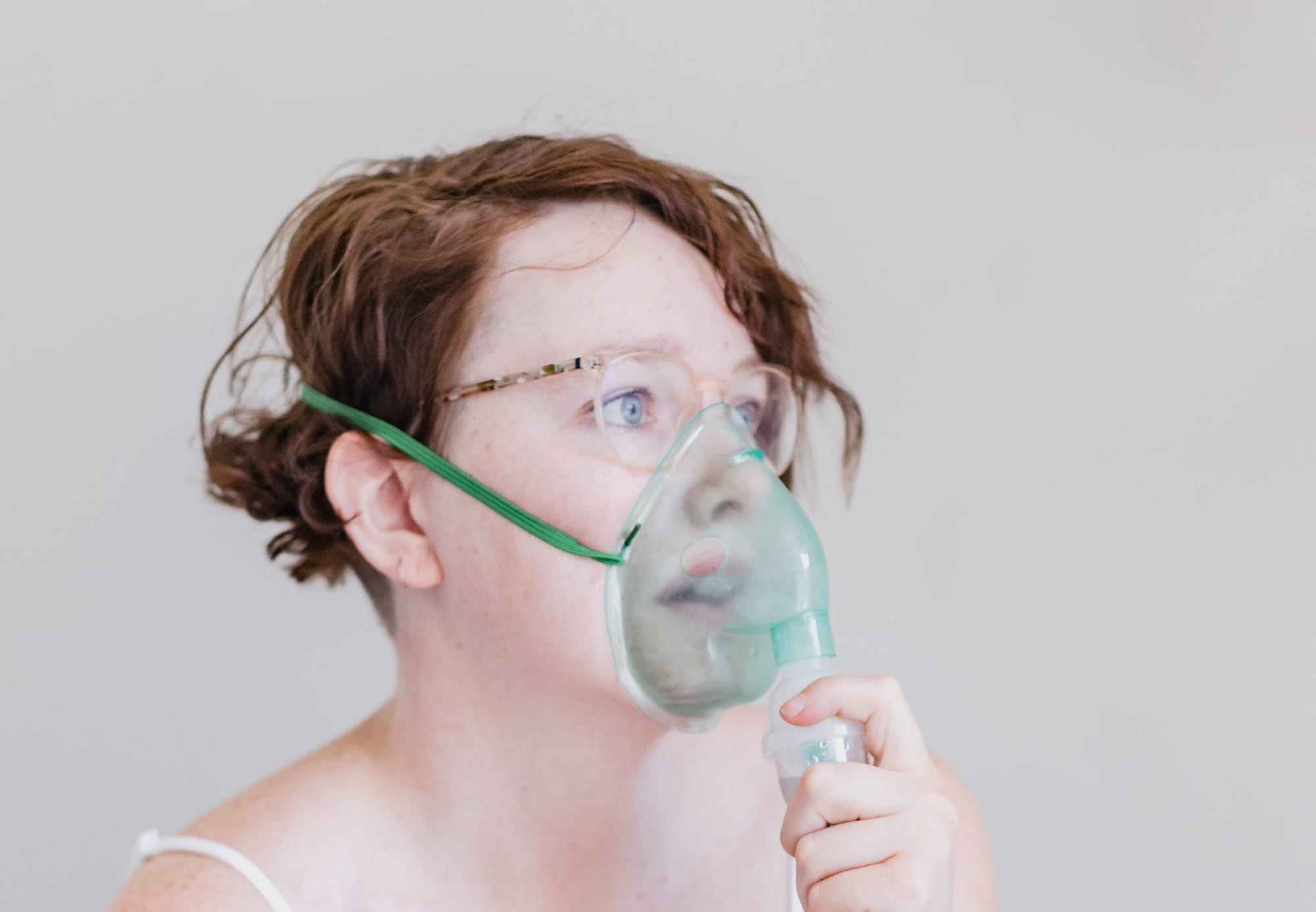 a woman sitting on a bed with a blow dryer in her mouth