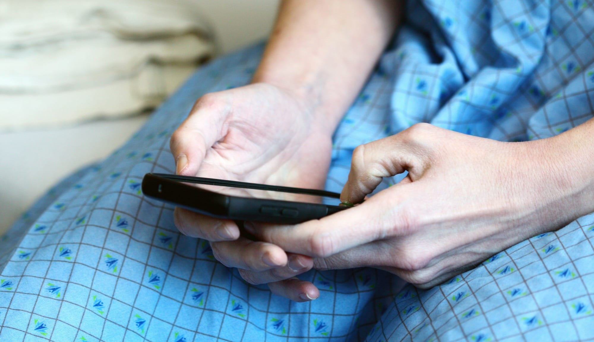 person in blue and white checkered button up shirt holding black smartphone