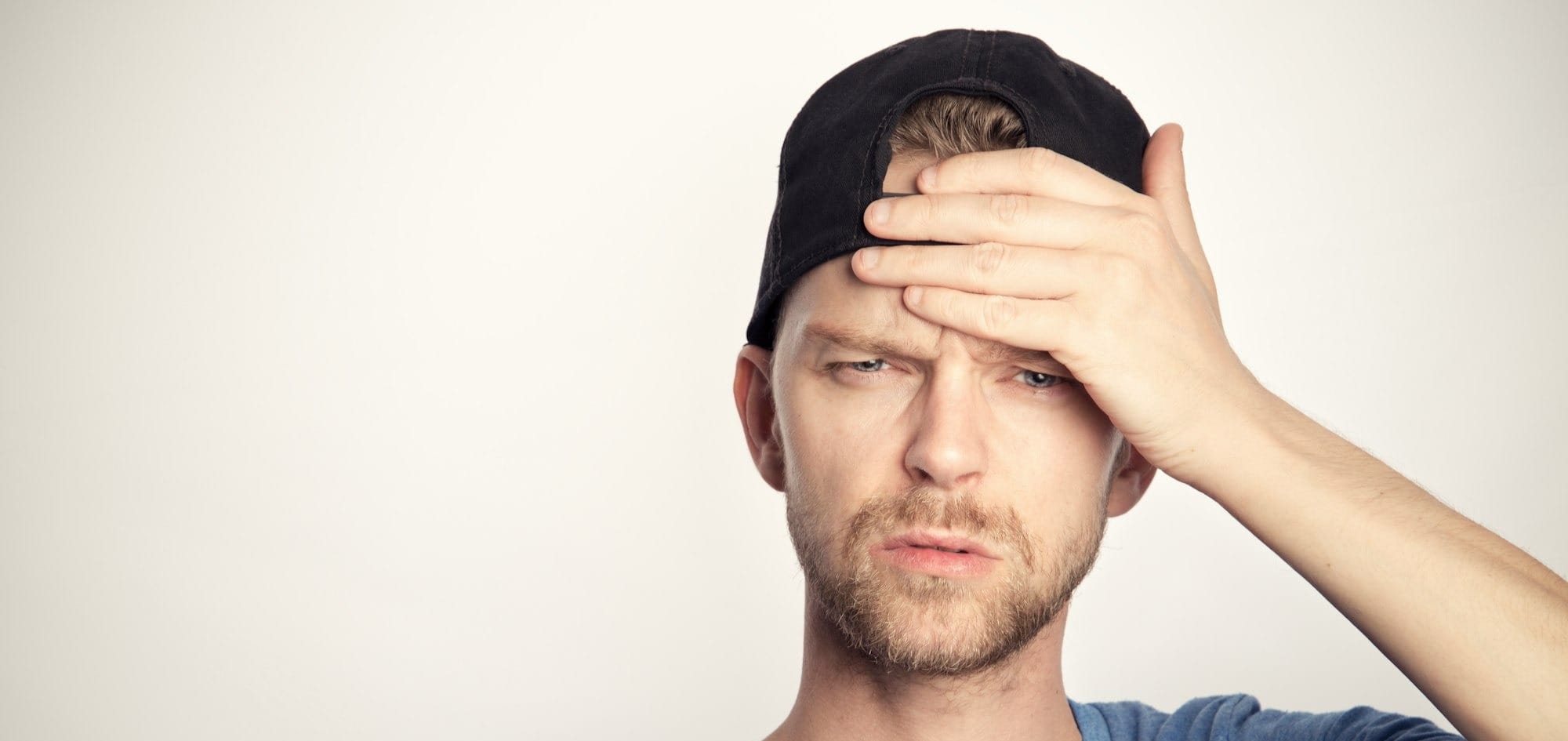 man in blue crew neck shirt covering his face