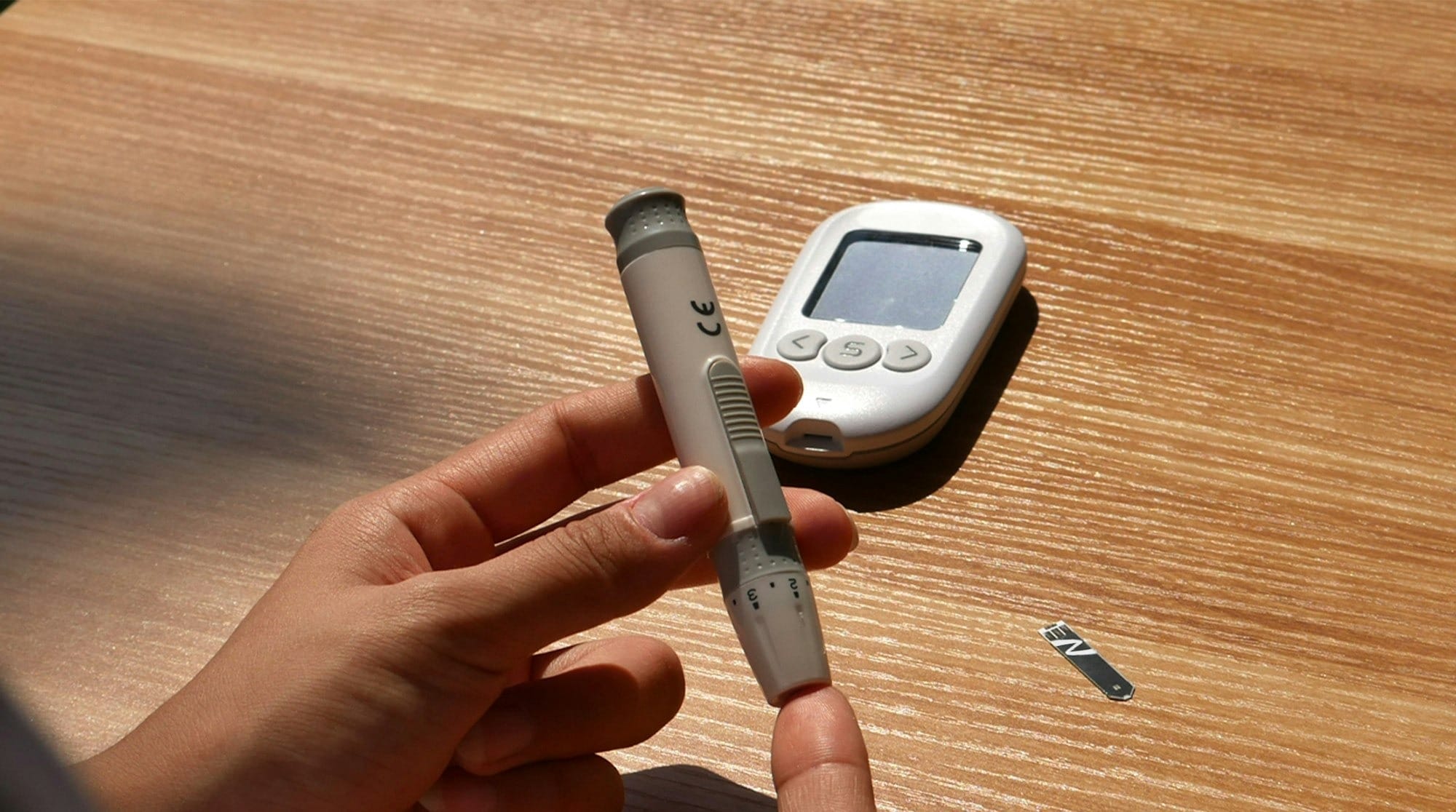 a person holding a pen and a cell phone on a table